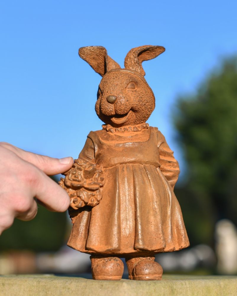 Rustic cast iron rabbit garden sculpture with hand for scale