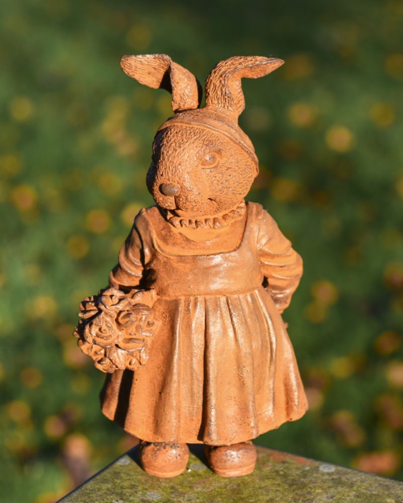 Rustic cast iron rabbit garden sculpture with lawn behind 