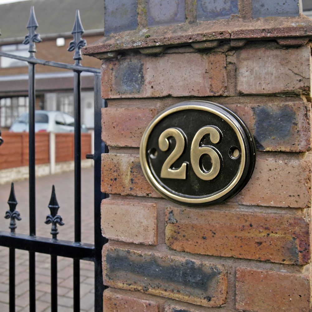 Polished Brass & Black Oval House Number Sign in Situ on a Brick Wall