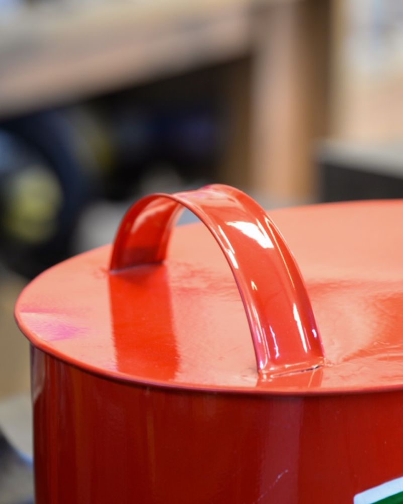 Red painted carry handle on the lid of a retro Ferrari oil can, close-up picture