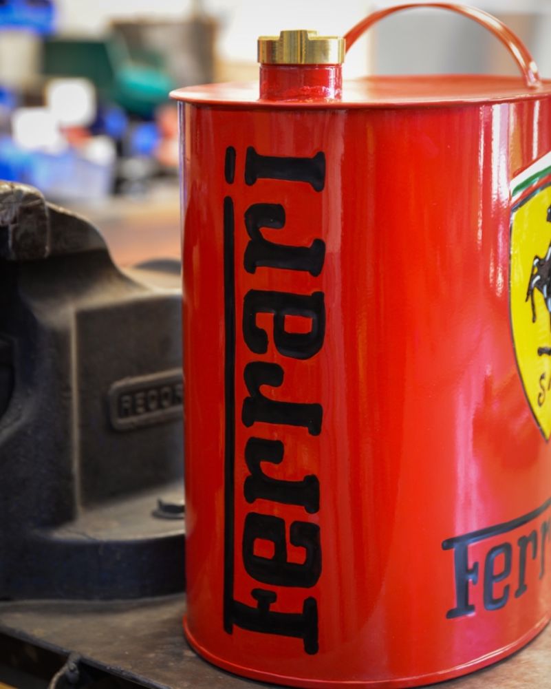Red, retro, metal Ferrari oil can. Side on view hand-painted Ferrari word-mark logo and brass filler cap