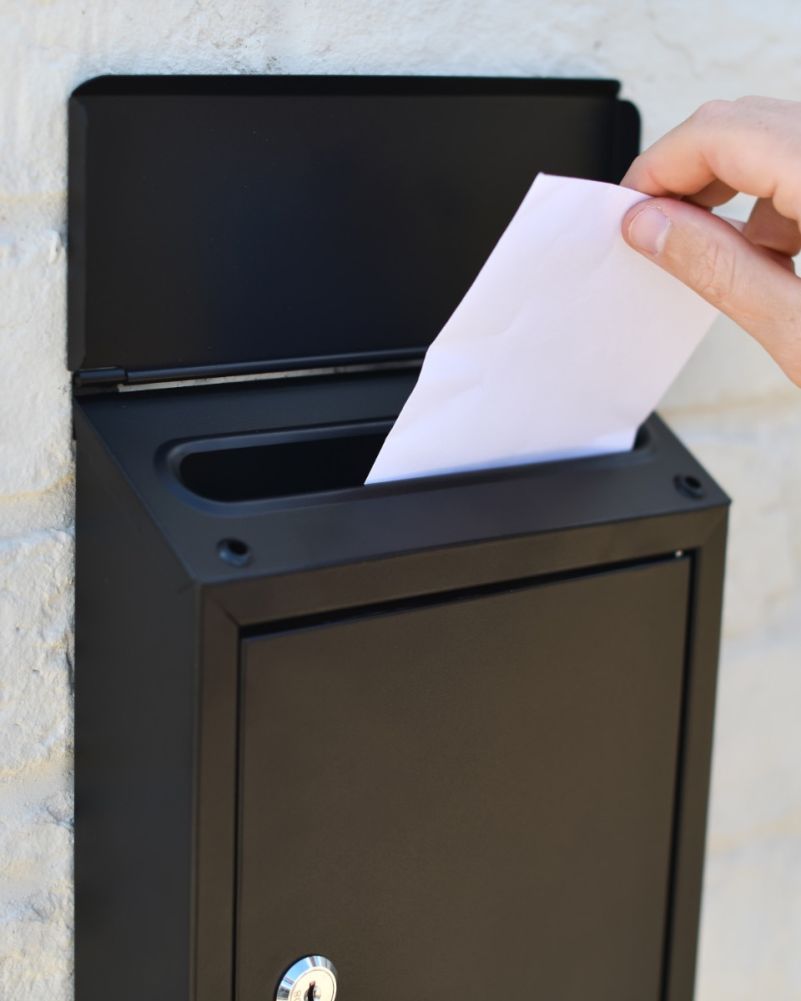Putting Letters Into The Steel Wall Mounted Contemporary Slanted Post Box In Black