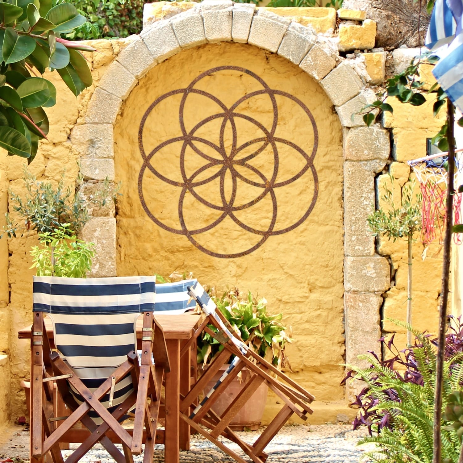 Rustic "Seed of Life" Steel Wall Art on a Yellow Garden Wall